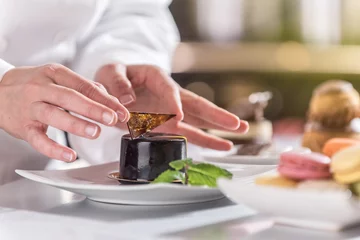 Selbstklebende Fototapeten closeup on hands of a pastry chef depositing a chocolate leaf © jackfrog