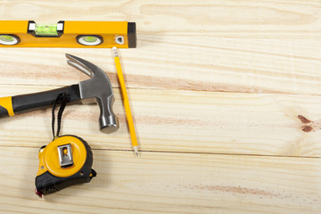 Hammer, level and tape measure laying on a wodden background