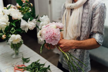 Male florist preparing bouquet of peones