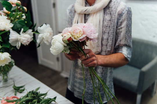 Male florist preparing bouquet of peones