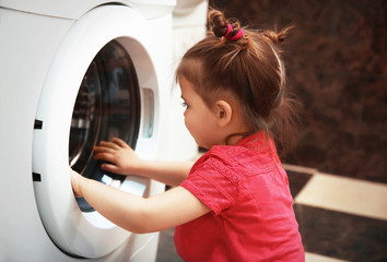 Little girl playing with washing machine