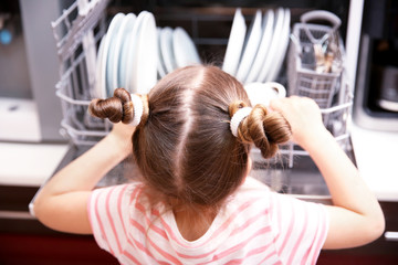 Fototapeta premium Little girl playing with dishwasher in kitchen