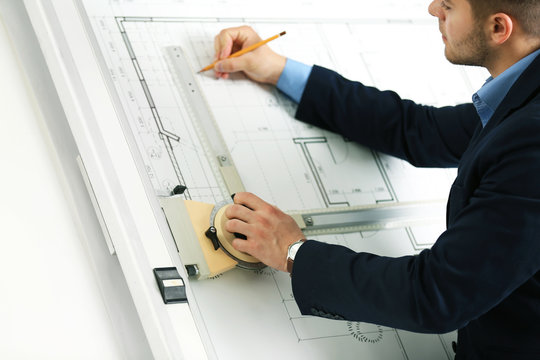Engineer working with blueprint on panel board indoors