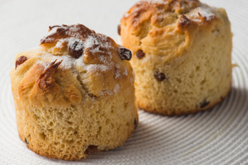 pair of homemade carrot muffins on white fabric background. top view