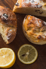 Top view of muffin with lemon in cup and on wooden plank table