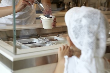 Confectioner decorating ice cream with berry in store