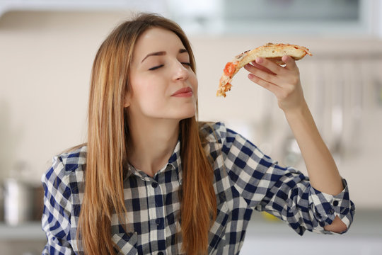 Happy Young Woman Eating Slice Of Hot Pizza At Home