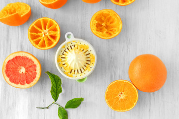 Juicy slices of oranges and juicer on white wooden table