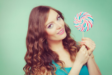 Smiling girl with lollipop candy on teal