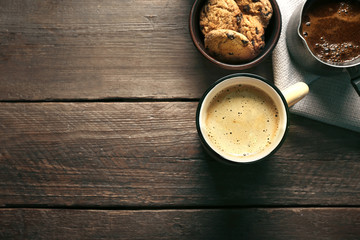 Mug of coffee with cookies on wooden table