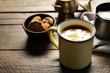 Mug of coffee with cookies on wooden table