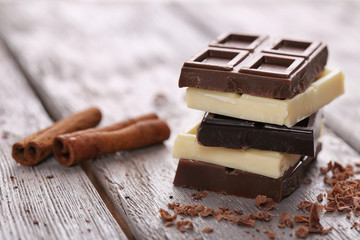 Mix of chocolate with cinnamon sticks on wooden table