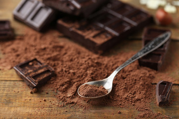 Spoon with cocoa powder and dark chocolate on table