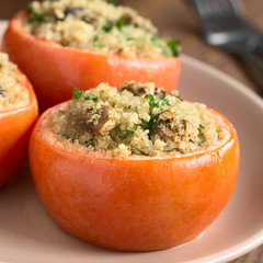 Gebackene Tomaten gefüllt mit Quinoa, Champignon und Petersilie, fotografiert mit natürlichem Licht (Selektiver Fokus, Fokus auf die Vorderseite der Champignons in der ersten Tomate)