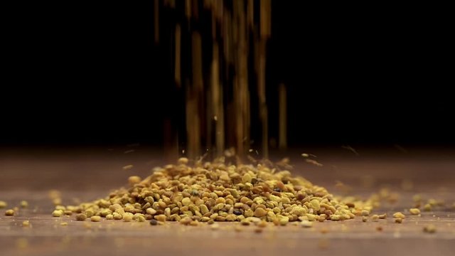 Lentil falling down on a wooden table on a black background. Slow motion. Close up