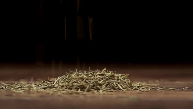 Cumin falling on a wooden table on a black background. Slow motion. Close up