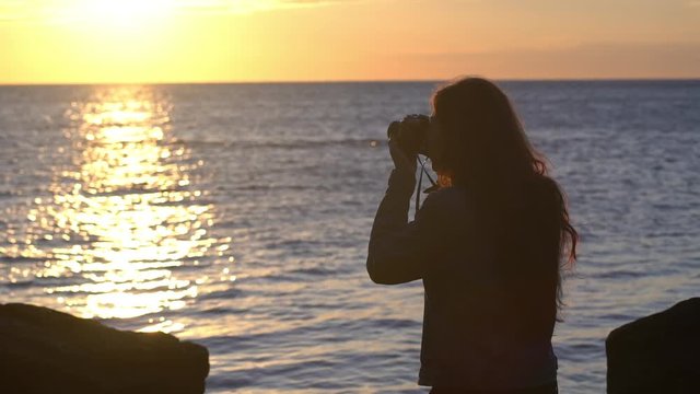 Beautiful brunette photographer at the coastline. Close up. Slow motion