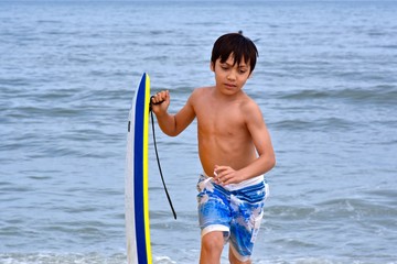 Young boy boogie boarding at the beach