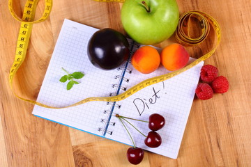 Fruits and centimeter with notebook, slimming and healthy food