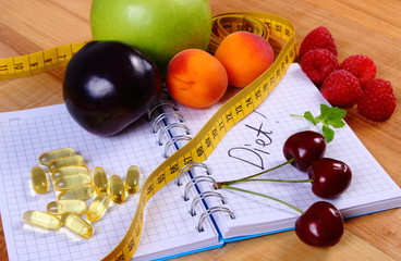Fruits, tablets supplements and centimeter with notebook, slimming and healthy food