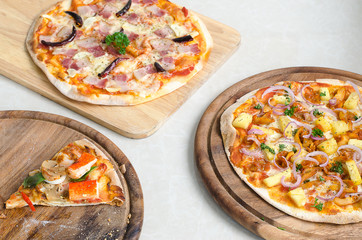 Slice of Seafood Italian Pizza and Hawaiian Chicken BBQ Italian Pizza and Bacon,Garlic and Chilli Italian Pizza on wood dish 