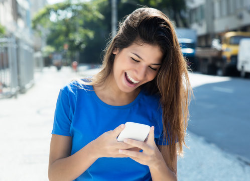 Frau im blauen Shirt surft mit Handy