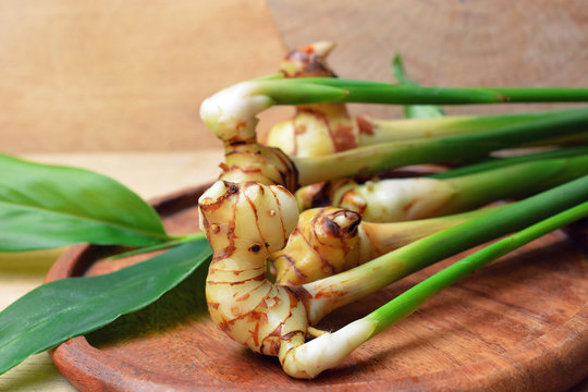 young galangal root and fresh galangal leaf on wooden background. thai herb.