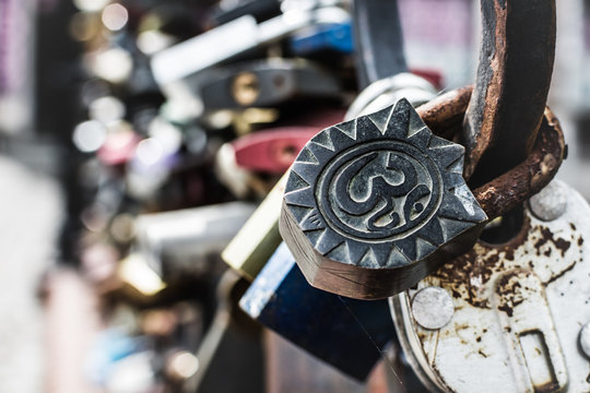 Rusty padlock with buddhist om symbol hanging on the raling of Love Bridge in Gdansk, Poland. 