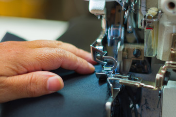 Woman hand holding the black fabric, close up of sewing machine