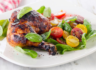 Roasted chicken leg with fresh vegetables.