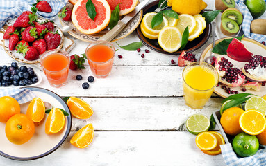 Citrus juice, fresh fruits and berries on a white wooden backgro