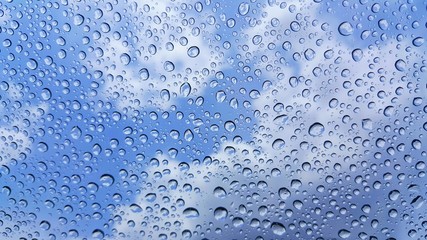 Raindrops on glass and blurred sky background