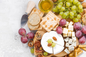 camembert, grapes and snacks on a white background, top view