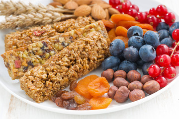 cereal muesli bars, fresh and dried fruit on a plate, closeup
