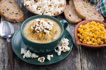 corn soup with popcorn in cup on wooden table