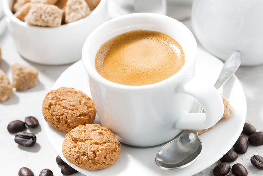 cup of espresso and cookies on a white table, closeup
