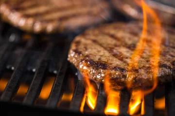 Crédence de cuisine en verre imprimé Grill / Barbecue Plusieurs hamburgers sur la grille avec des flammes au premier plan