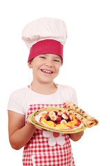 happy little girl cook with crepes on plate