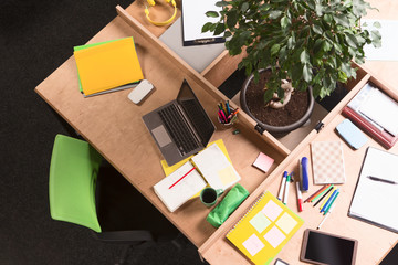 Top view of working place in office. Business mess on working table. Nobody sitting at table. Laptop computer. Documents.