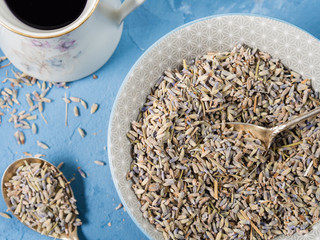 Lavender flowers in a bowl and lavender syrup on blue textured background
