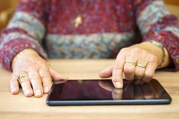 old woman is using tablet computer to surf on internet