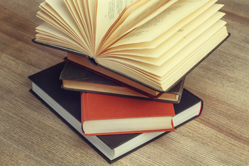 Libro apilados y uno abierto sobre una mesa de madera rústica. Vista superior y de cerca