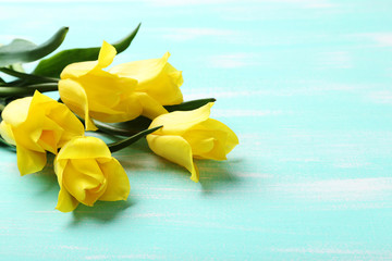 Bouquet of yellow tulips on a mint wooden table