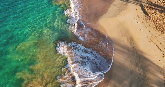 Aerial view flying over tropical white sand beach at sunrise