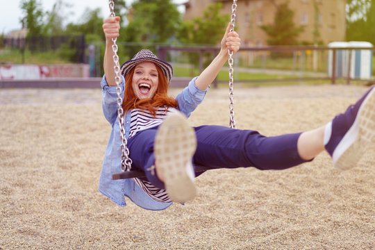 lachende frau schaukelt auf einem spielplatz