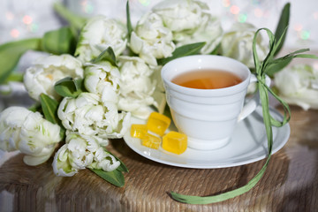 Чай в белой чашке, мармелад и букет тюльпанов