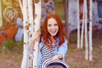 lachende junge frau hält ihren hut nach vorne