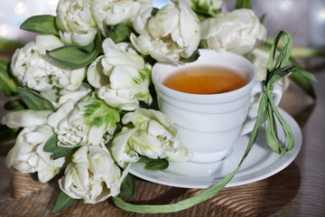 Чай в белой чашке и букет тюльпанов