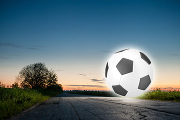 Fototapeta na wymiar Shining soccer ball on a road