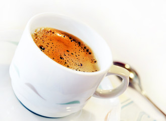 Cup of coffee with saucer and teaspoon on white background